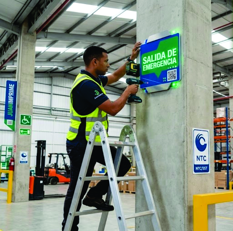 Operario de JuanImprime instalando señalización industrial en bodega de Cali